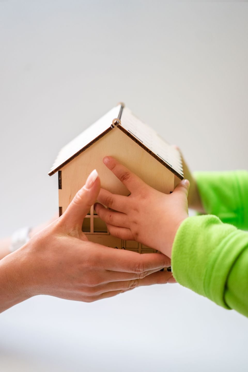 Hands holding a wooden model home